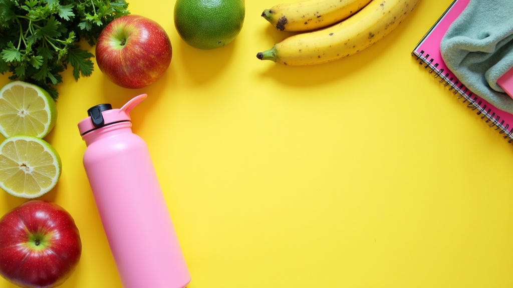 Colorful flat lay of healthy foods, workout gear, notebook, and a bottle of water surrounding a bright, inviting table. No people or text included.